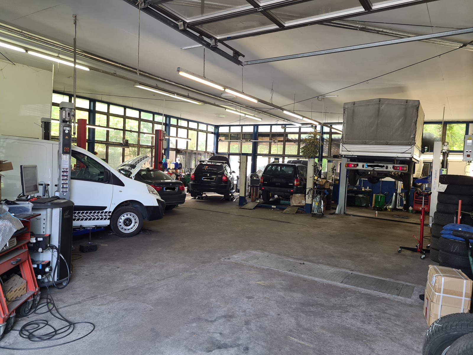 Blick in die Werkstatthalle der Autohaus Noack GmbH: mehrere Hebebühnen mit PKW und Transportern
